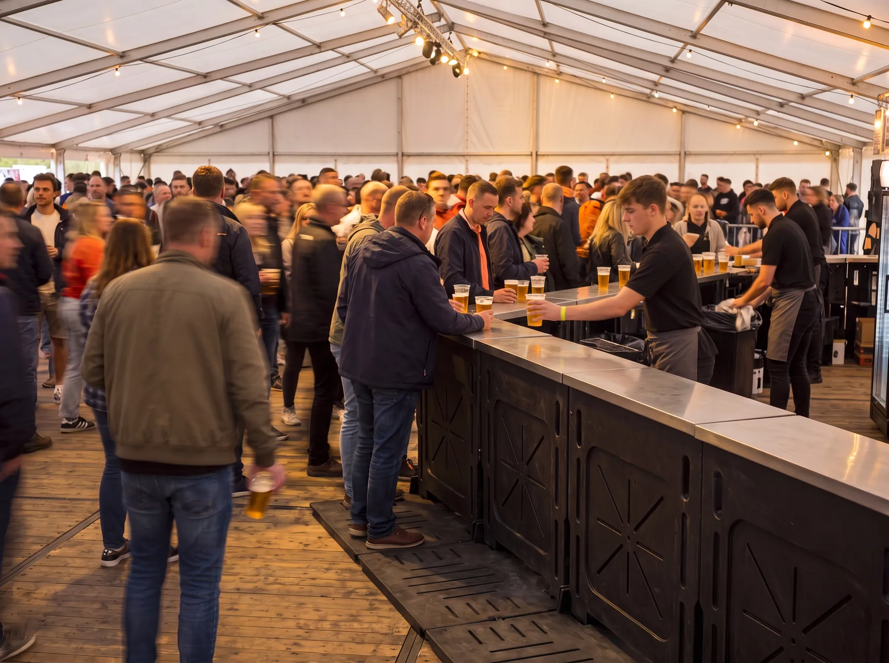 Barpersoneel geeft bekers bier uit over een rij bar/buffet barriers van Freyja